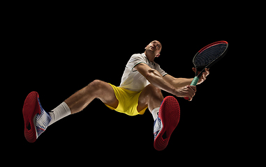 Image showing Young caucasian tennis player in action, motion isolated on black background, look from the bottom. Concept of sport, movement, energy and dynamic.