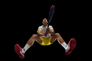 Image showing Young caucasian tennis player in action, motion isolated on black background, look from the bottom. Concept of sport, movement, energy and dynamic.