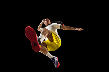 Image showing Young caucasian tennis player in action, motion isolated on black background, look from the bottom. Concept of sport, movement, energy and dynamic.