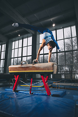 Image showing Little male gymnast training in gym, flexible and active. Caucasian fit little boy, athlete in sportswear practicing in exercises for strength, balance.