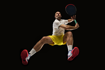 Image showing Young caucasian tennis player in action, motion isolated on black background, look from the bottom. Concept of sport, movement, energy and dynamic.