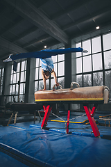 Image showing Little male gymnast training in gym, flexible and active. Caucasian fit little boy, athlete in sportswear practicing in exercises for strength, balance.