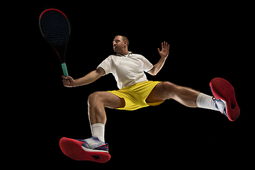 Image showing Young caucasian tennis player in action, motion isolated on black background, look from the bottom. Concept of sport, movement, energy and dynamic.