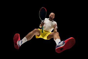 Image showing Young caucasian tennis player in action, motion isolated on black background, look from the bottom. Concept of sport, movement, energy and dynamic.