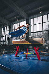 Image showing Little male gymnast training in gym, flexible and active. Caucasian fit little boy, athlete in sportswear practicing in exercises for strength, balance.