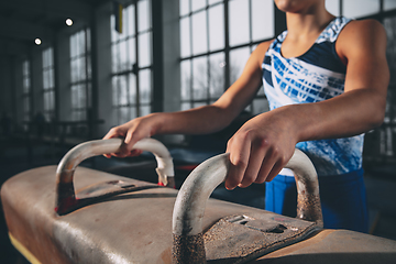 Image showing Little male gymnast training in gym, flexible and active. Caucasian fit little boy, athlete in sportswear practicing in exercises for strength, balance.