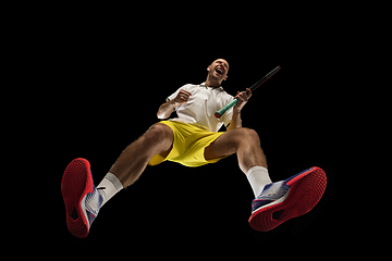 Image showing Young caucasian tennis player in action, motion isolated on black background, look from the bottom. Concept of sport, movement, energy and dynamic.