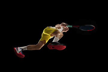 Image showing Young caucasian tennis player in action, motion isolated on black background, look from the bottom. Concept of sport, movement, energy and dynamic.