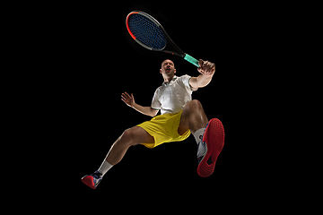 Image showing Young caucasian tennis player in action, motion isolated on black background, look from the bottom. Concept of sport, movement, energy and dynamic.