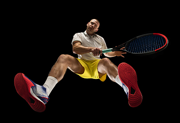 Image showing Young caucasian tennis player in action, motion isolated on black background, look from the bottom. Concept of sport, movement, energy and dynamic.