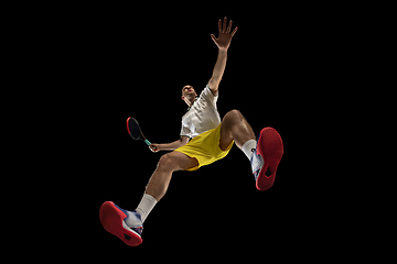 Image showing Young caucasian tennis player in action, motion isolated on black background, look from the bottom. Concept of sport, movement, energy and dynamic.