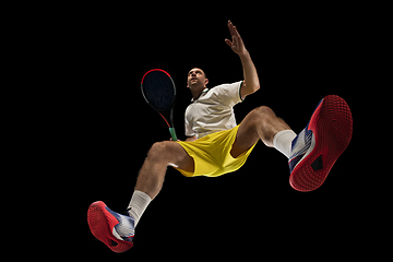 Image showing Young caucasian tennis player in action, motion isolated on black background, look from the bottom. Concept of sport, movement, energy and dynamic.