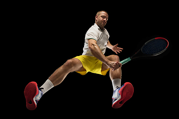 Image showing Young caucasian tennis player in action, motion isolated on black background, look from the bottom. Concept of sport, movement, energy and dynamic.