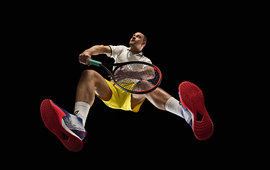 Image showing Young caucasian tennis player in action, motion isolated on black background, look from the bottom. Concept of sport, movement, energy and dynamic.