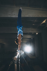 Image showing Little male gymnast training in gym, flexible and active. Caucasian fit little boy, athlete in sportswear practicing in exercises for strength, balance.