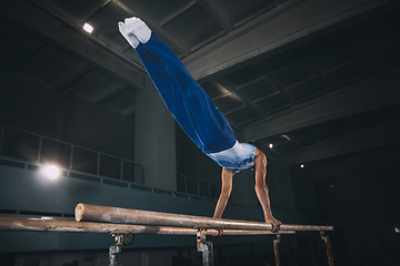 Image showing Little male gymnast training in gym, flexible and active. Caucasian fit little boy, athlete in sportswear practicing in exercises for strength, balance.