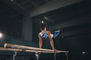 Image showing Little male gymnast training in gym, flexible and active. Caucasian fit little boy, athlete in sportswear practicing in exercises for strength, balance.