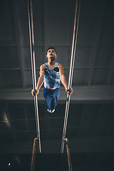 Image showing Little male gymnast training in gym, flexible and active. Caucasian fit little boy, athlete in sportswear practicing in exercises for strength, balance.