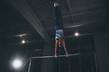 Image showing Little male gymnast training in gym, flexible and active. Caucasian fit little boy, athlete in sportswear practicing in exercises for strength, balance.