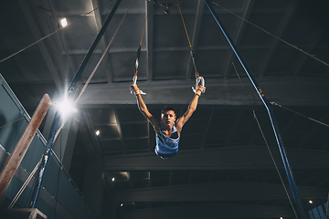 Image showing Little male gymnast training in gym, flexible and active. Caucasian fit little boy, athlete in sportswear practicing in exercises for strength, balance.