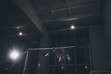 Image showing Little male gymnast training in gym, flexible and active. Caucasian fit little boy, athlete in sportswear practicing in exercises for strength, balance.