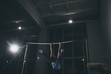 Image showing Little male gymnast training in gym, flexible and active. Caucasian fit little boy, athlete in sportswear practicing in exercises for strength, balance.