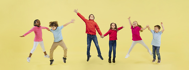 Image showing Little and happy kids gesturing isolated on yellow studio background. Human emotions, facial expression concept