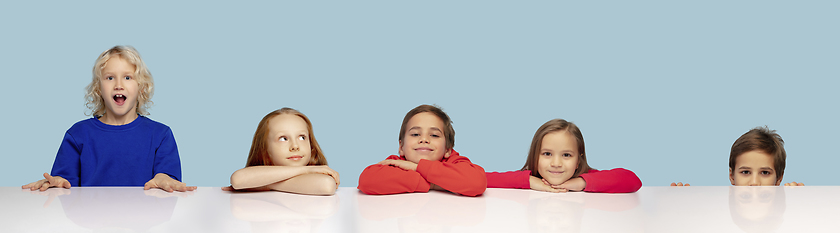 Image showing Little and happy kids gesturing isolated on blue studio background. Human emotions, facial expression concept