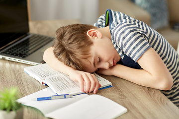 Image showing tired student boy sleeping on desk at home