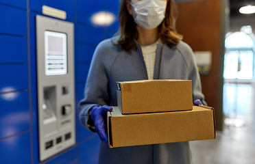 Image showing woman in mask with boxes at parcel machine