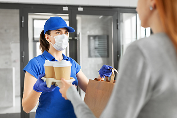 Image showing delivery girl in mask giving paper bag to customer