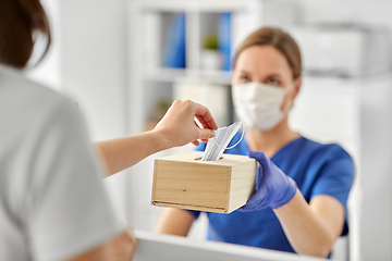 Image showing doctor offering mask to patient at hospital