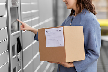 Image showing smiling woman with box at automated parcel machine