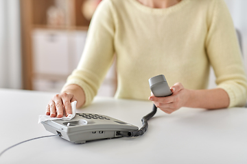 Image showing close up of woman cleaning desk phone with tissue