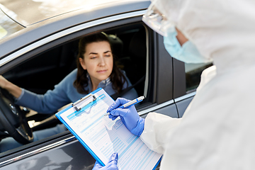 Image showing healthcare worker with clipboard and woman in car