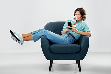 Image showing happy woman with smartphone sitting in armchair