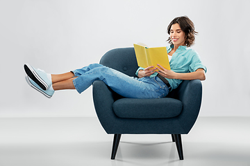 Image showing happy young woman in armchair reading book