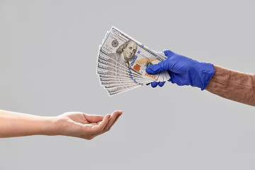 Image showing close up of hand in medical glove giving money