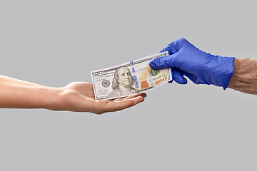 Image showing close up of hand in medical glove giving money