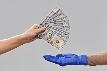 Image showing close up of hand in medical glove giving money