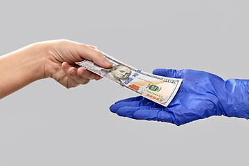 Image showing close up of hand in medical glove giving money