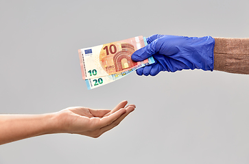 Image showing close up of hand in medical glove giving money