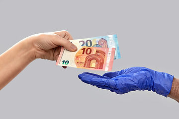 Image showing close up of hand in medical glove giving money