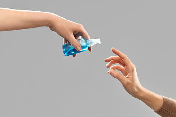 Image showing close up of hands giving each other gel sanitizer