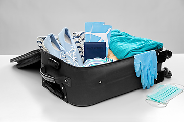 Image showing travel bag packed with clothes, gloves and masks