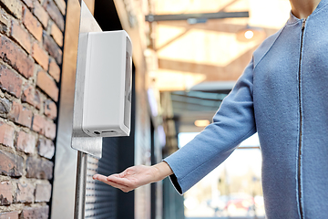 Image showing close up of woman at dispenser with hand sanitizer