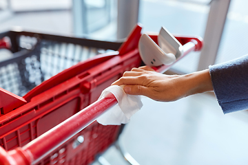 Image showing hand cleaning shopping cart handle with wet wipe