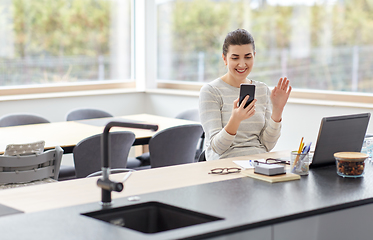 Image showing woman with cellphone has video chat at home office