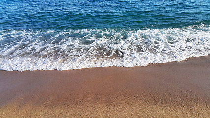 Image showing Sea wave with white foam on the sandy beach