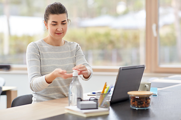 Image showing woman spraying hand sanitizer at home office